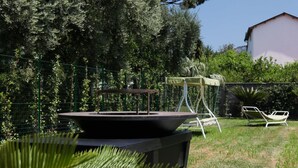 Een terras met een tafel en stoelen, omringd door een hek en begroeiing.