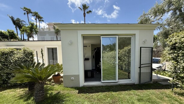Een modern gelijkvloers huis met een schuifdeur, een klein terras en een verzorgd gazon.