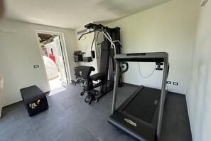 Een huisgymnasium met een loopband, gewichtbank en trainingsapparatuur.