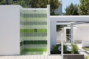 A modern outdoor shower area with green and white patterned tiles, a metal showerhead, and a white bench. - Villa Massa residence Sorrento (Sant Agnello)