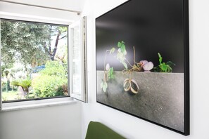 Une pièce dotée d’une grande fenêtre et ornée d’une œuvre d’art murale représentant une plante chargée de fruits.