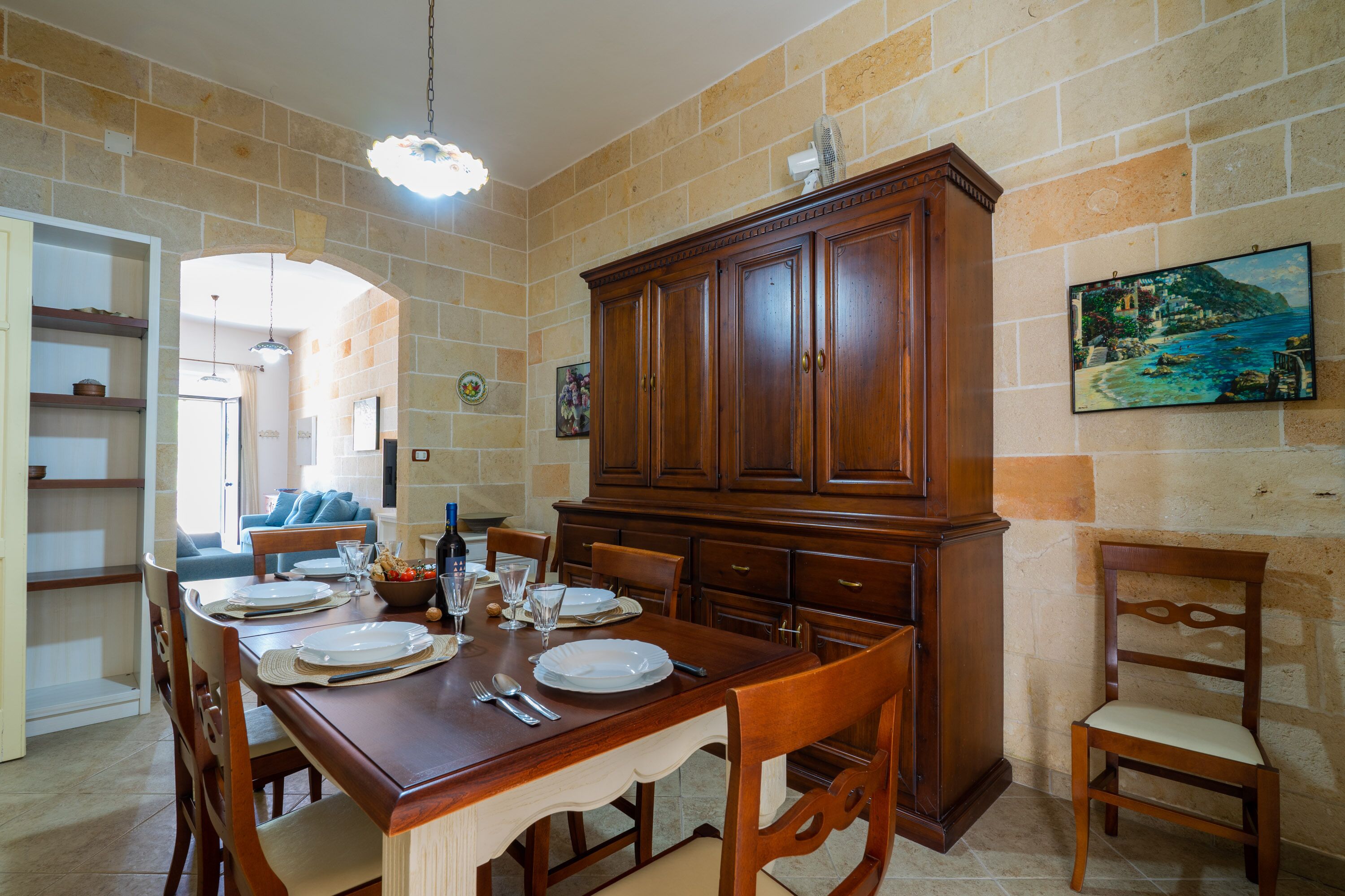 A dining area with a wooden table set for four, flanked by a large cabinet and a chair.