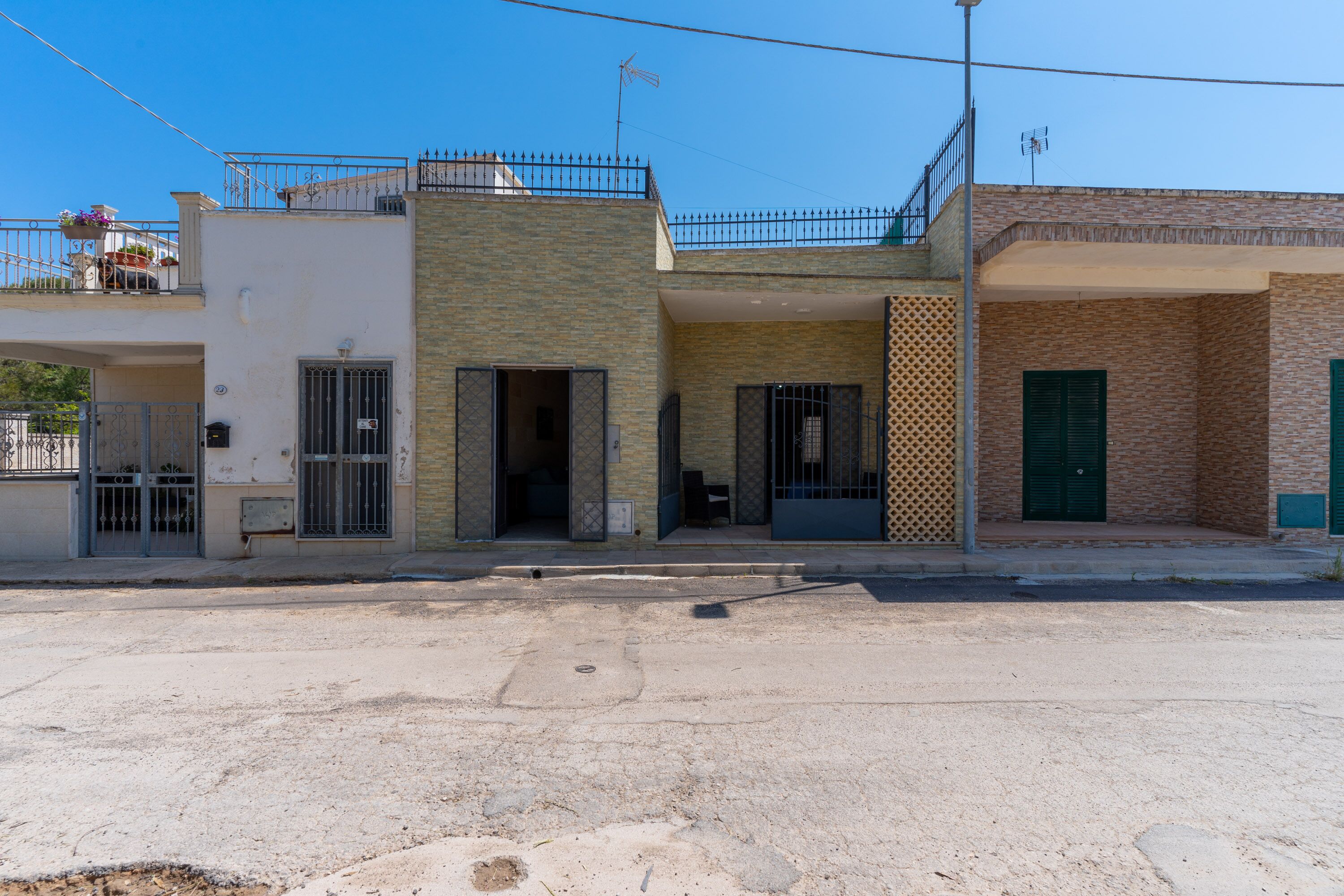 A two-story building with a balcony, a gated entrance, and a visible door.