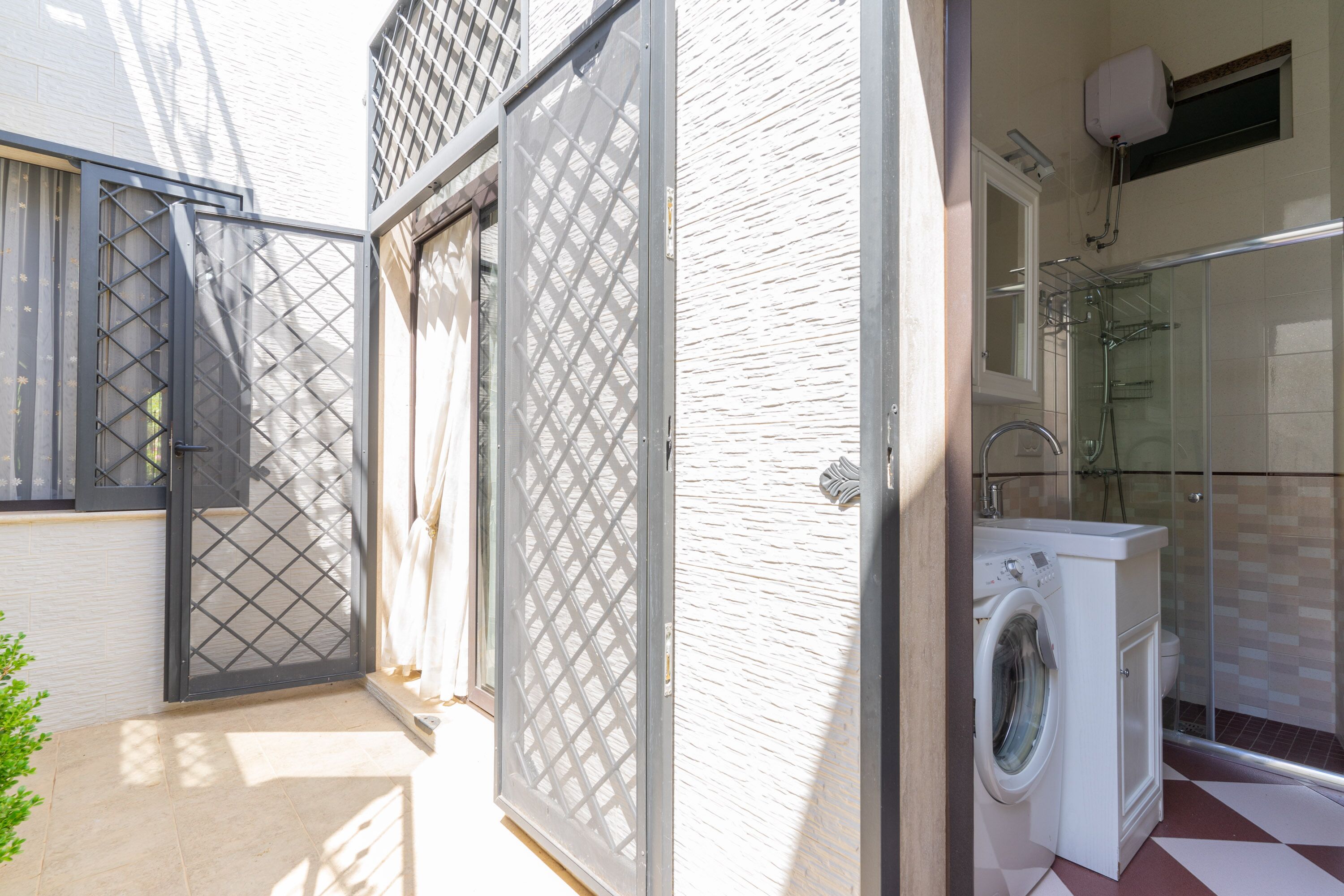 A compact bathroom with a washing machine, a shower, and a toilet.