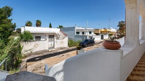 Eine Wohnstraße mit Häusern, einem geparkten Auto und einem Blumentopf auf einem Balkon.