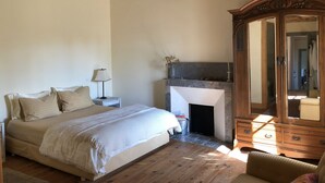 Une chambre à coucher comprenant un lit, une table de chevet, une lampe, une cheminée et une armoire en bois.