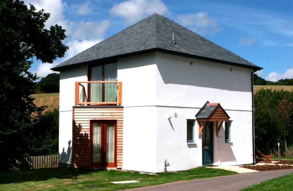 A two-story house with a white exterior, a sloped roof, and a small attached garage.
