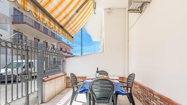 A balcony with a table set for two, metal chairs, and a striped awning. - 3381 Casa Savina by Barbarhouse (Porto Cesareo)