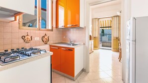 A kitchen with orange cabinets, a white countertop, and a stainless steel sink. - 3381 Casa Savina by Barbarhouse (Porto Cesareo)