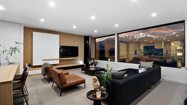 A modern living room with a large window, a fireplace, and a television.