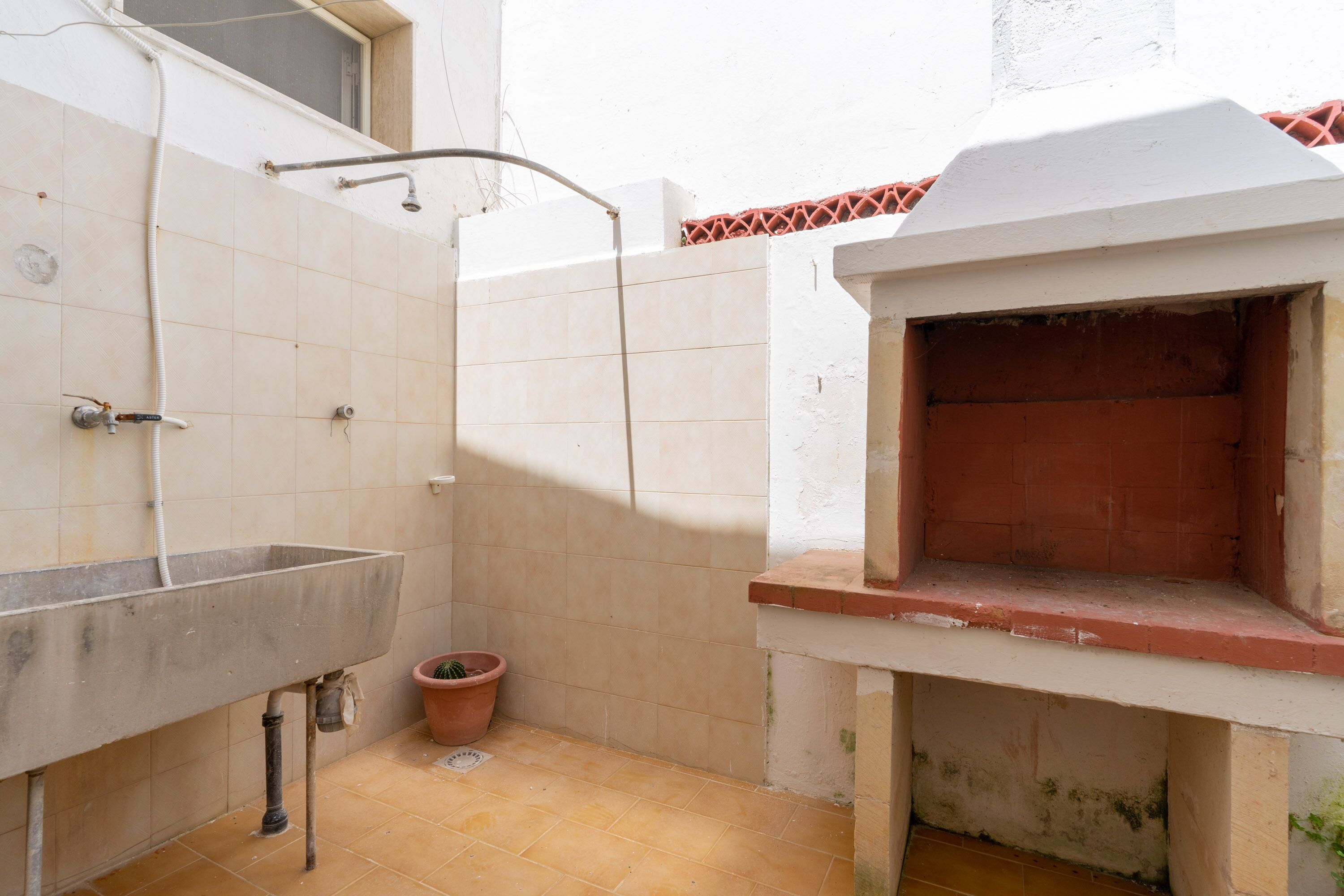 A small, enclosed bathroom with a sink, shower, and a tiled wall.