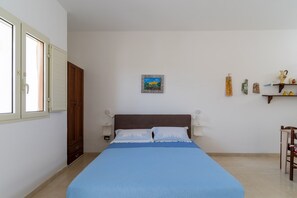 Une chambre à coucher comprenant un lit, une armoire, une table de chevet, une étagère murale décorative et une fenêtre avec des rideaux.