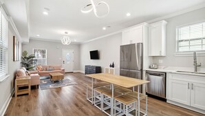 Una cocina moderna con muebles blancos, un refrigerador de acero inoxidable y un lavavajillas.