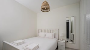 Une chambre à coucher avec un lit, une table de chevet, une lampe et un luminaire suspendu.