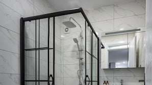 Une salle de bain moderne avec une douche à parois de verre, des toilettes et un lavabo avec un miroir au-dessus.