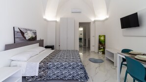Una habitación de hotel moderna con una cama, un escritorio, una silla y un televisor montado en la pared.