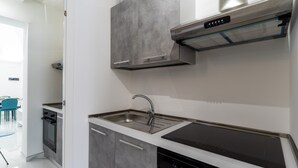 Una cocina moderna con un lavamanos de acero inoxidable, un horno empotrado y una placa vitrocerámica.