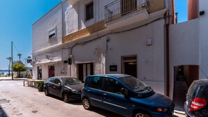 Vista de calle con un edificio que tiene un balcón y una puerta con un letrero.