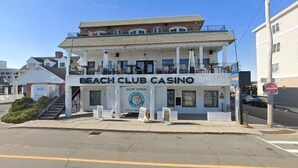 A two-story building with a sign reading "Beach Club Casino" and a "Now Open" banner. - Newly Renovated, all new beds and bedroom furniture (Hampton)