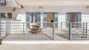 Un edificio moderno con un espacio exterior cubierto, una mesa de comedor y sillas.