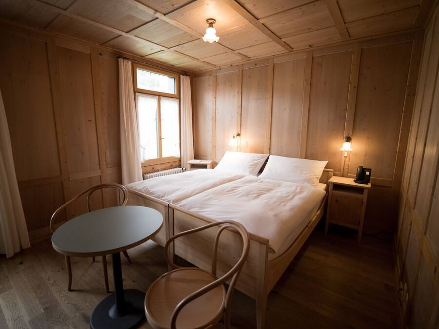 Una habitación de madera con una cama, una mesa y sillas.