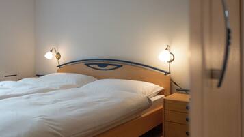 A bed with a wooden headboard, two bedside tables, and a wall-mounted lamp.