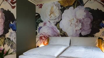 Une chambre à coucher avec un lit, un papier peint à motifs floraux et une table de chevet.