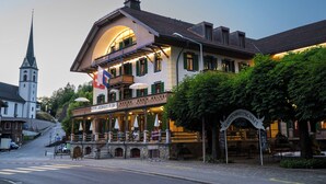 A historic building with a church steeple, a restaurant with outdoor seating, and a sign for Gartenwirtshaus.