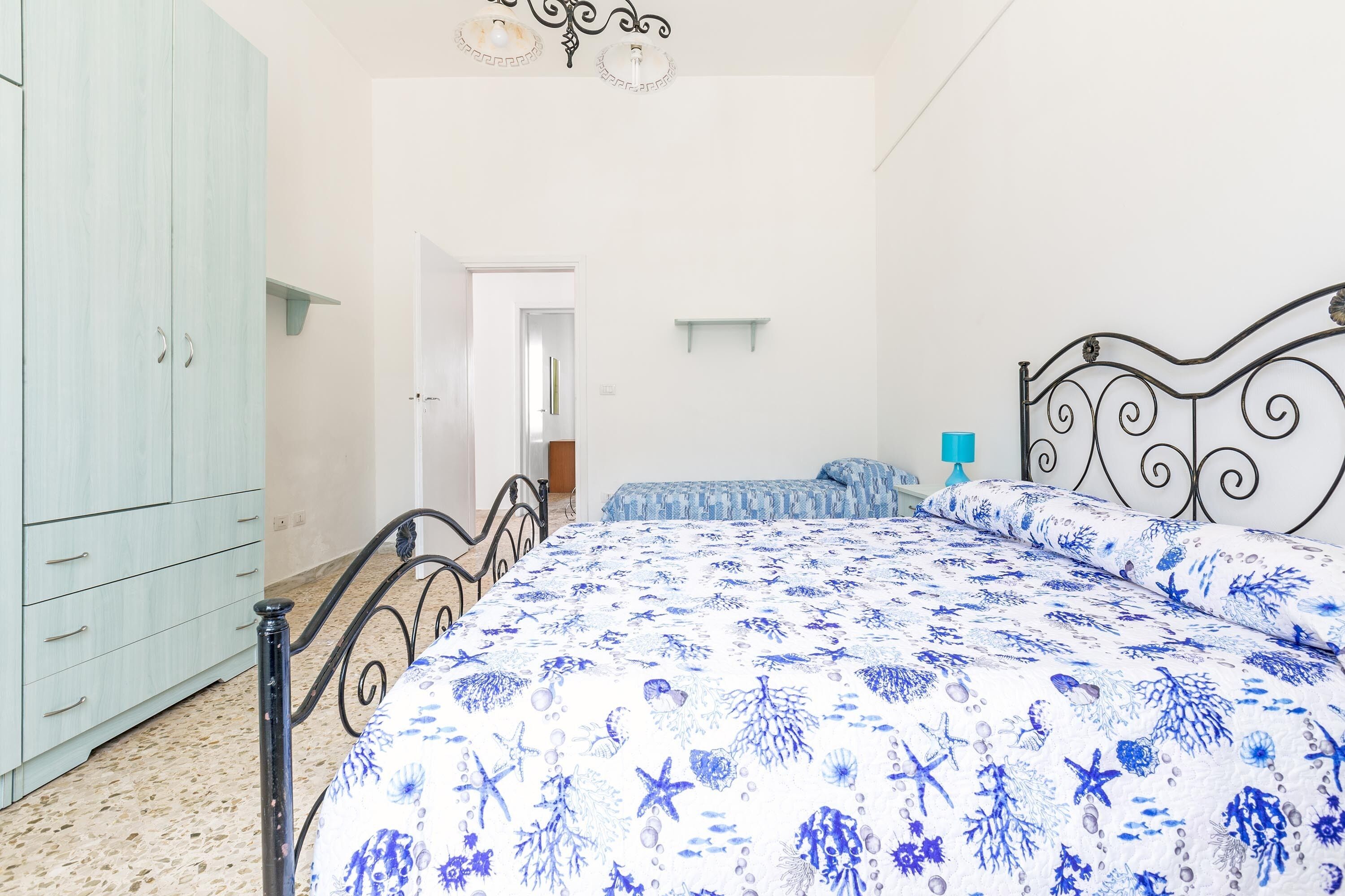 A bedroom with a bed, a wardrobe, and a door leading to another room.