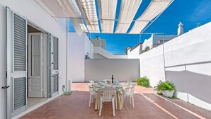 A patio with a table set for dining, surrounded by white walls and a white ceiling. - 3380 Marechiaro - Appartamento C by Barbarhouse (Porto Cesareo)