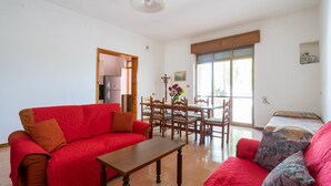 A living room with a red sofa, a wooden coffee table, and a dining area with wooden chairs and a table. - 3478 Atene - PT By Barbarhouse (Porto Cesareo)