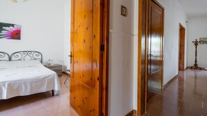 A bedroom with a bed, wooden wardrobe, and a painting on the wall. - 3478 Atene - PT By Barbarhouse (Porto Cesareo)