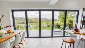 A modern kitchen with a large sliding glass door leading to a garden.