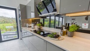 A modern kitchen with a large window, a flat-screen TV, and a variety of kitchen appliances.