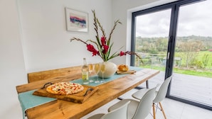 A dining table with a pizza, a vase with flowers, and glasses of wine.