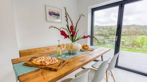 A dining table with a pizza, a vase with flowers, and glasses of wine.