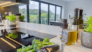 A kitchen counter with fresh vegetables, a bottle of olive oil, and a bottle of truffle oil.