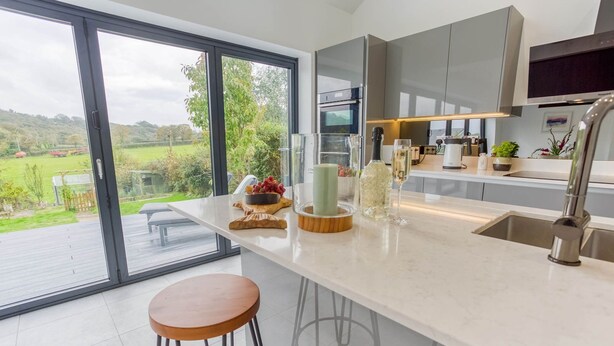 A modern kitchen with a large window, a built-in oven, and a stainless steel sink.