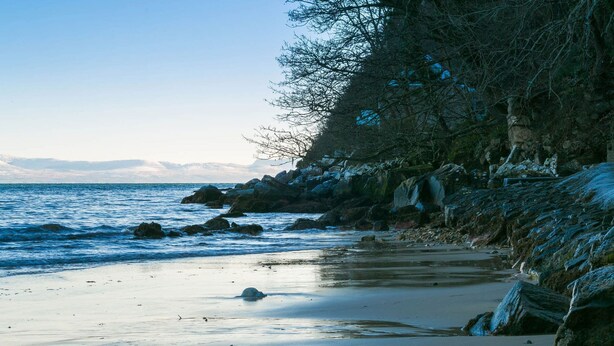 A coastal landscape with rocky cliffs, a sandy beach, and a calm sea. - Pencoed -  a coastal that sleeps 5 guests  in 3 bedrooms (Llanbedrog)