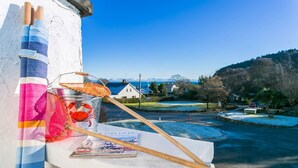 A rustic setting with a fishing rod, a net, and a magazine on a ledge overlooking a snowy landscape and a village. - Pencoed -  a coastal that sleeps 5 guests  in 3 bedrooms (Llanbedrog)