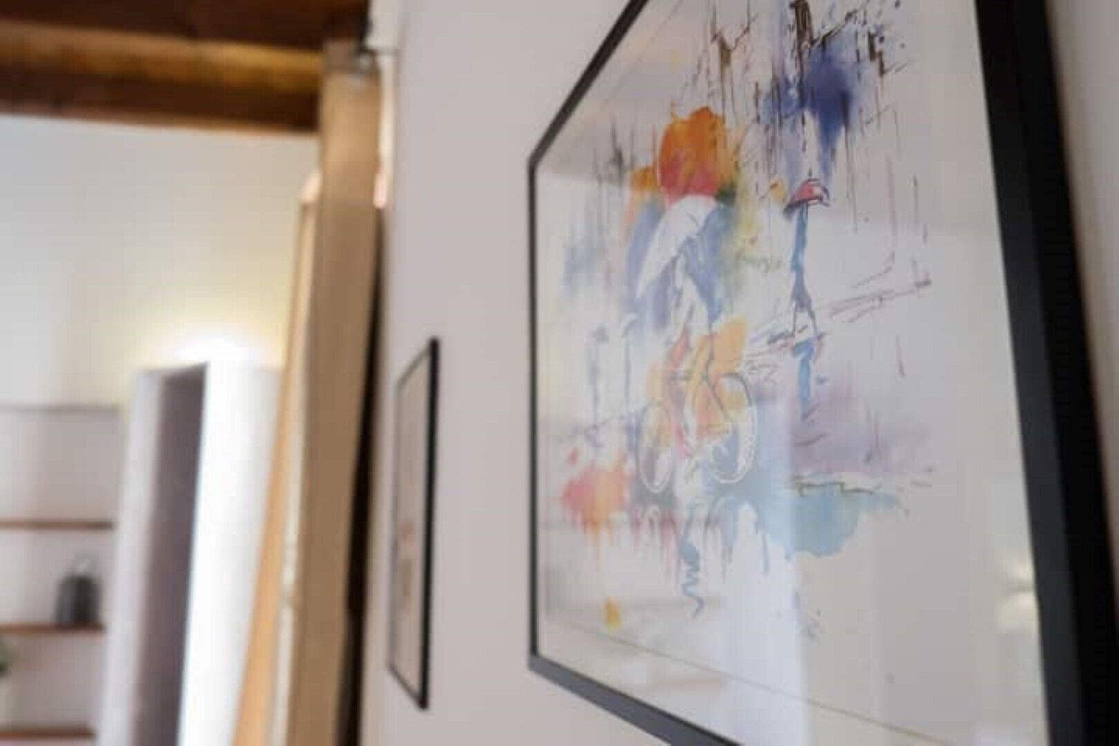 A hallway with framed artwork on the walls and a wooden ceiling.