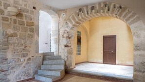 A stone-walled interior with a staircase leading to a door.