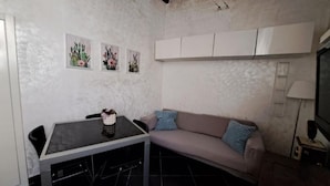 Un espace de vie compact comprenant un coin cuisine, une table à manger, un canapé et un téléviseur.