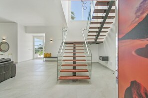 A modern interior with a glass staircase, a sofa, and a painting. - Palmas 15: Luxury villa w/ mosquito net, lap-pool, Jacuzzi, staff & golf cart (Punta Cana)