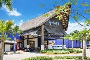 A BlueMall with a thatched roof entrance, palm trees, and a blue exterior wall. - Palmas 15: Luxury villa w/ mosquito net, lap-pool, Jacuzzi, staff & golf cart (Punta Cana)