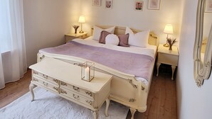 Un dormitorio con una cama grande, mesitas de noche con lámparas, un espejo y cuadros en la pared.