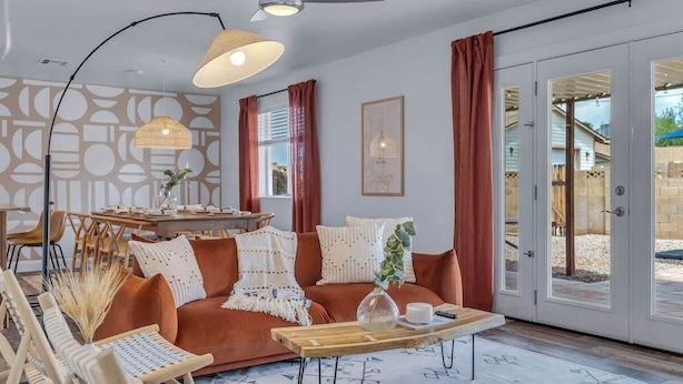 A modern living room with a sofa, coffee table, and dining area. - Sun & Fun, Backyard and Pool (Tempe)