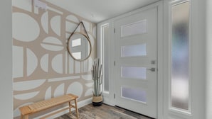 A hallway with a wooden bench, a wall with geometric patterns, a frosted glass door, and a potted plant. - Sun & Fun, Backyard and Pool (Tempe)