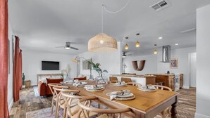 A spacious dining area with a wooden table set for six, surrounded by woven chairs. - Sun & Fun, Backyard and Pool (Tempe)