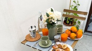 Ein Frühstückstisch mit Stühlen, einer Kaffeekanne, Orangensaft, einer Auswahl an Gebäck und einer Vase mit Blumen.